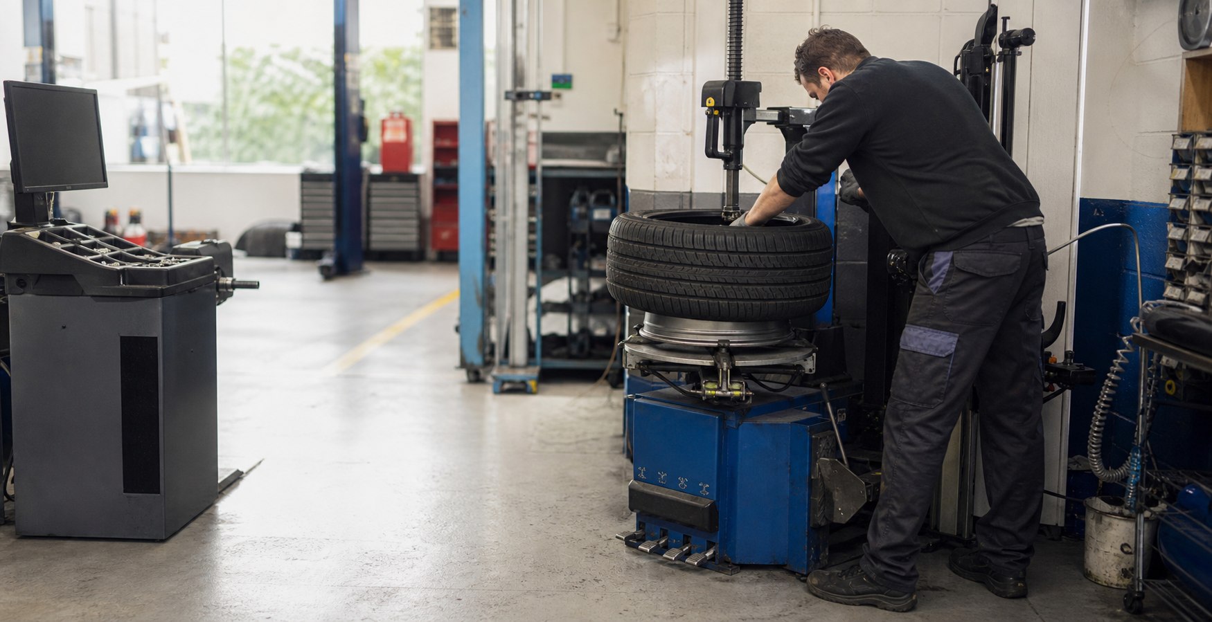 Technician fitting a tyre using professional workshop equipment
